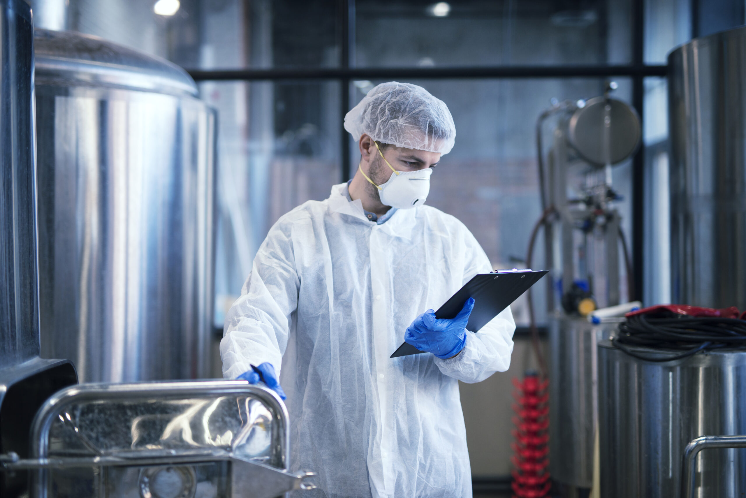 industrial worker white protective clothes holding checklist reading results scaled